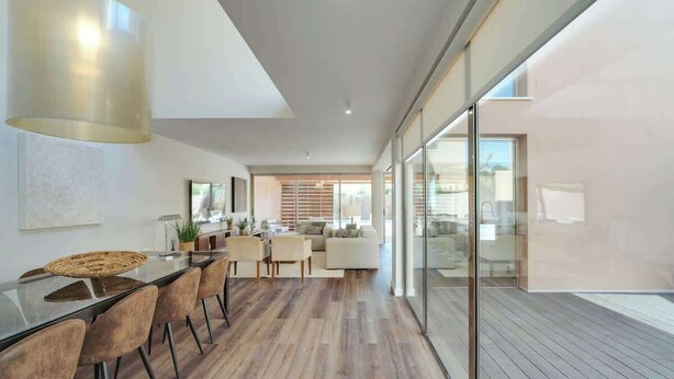 Un interno moderno con zona pranzo, salotto e parete in vetro.