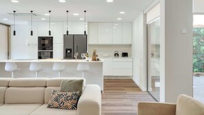 Una cucina moderna con mobili bianchi, un'isola centrale e luci a sospensione.