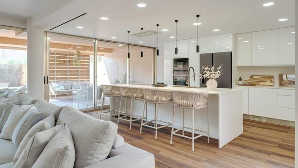 A modern kitchen with a bar area, wooden flooring, and a seating area with a sofa. - 4BR Villa w/ Private Pool | Salgados | DA’Home (Guia)