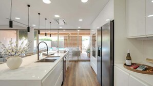 A modern kitchen with a central island, stainless steel appliances, and a view to an outdoor area. - 4BR Villa w/ Private Pool | Salgados | DA’Home (Guia)