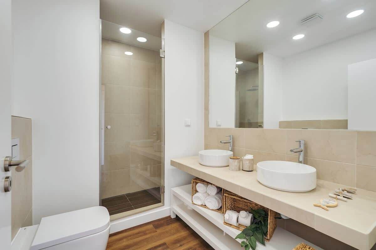 A modern bathroom with a glass shower enclosure, a white sink, and a large mirror.