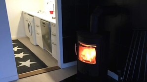 Habitación con estufa de leña, lavadora y zona de cocina.