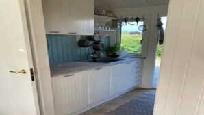A narrow kitchen with white cabinets and a wooden countertop. - 5 Star Holiday Home in Dronningmolle (Dronningmolle)