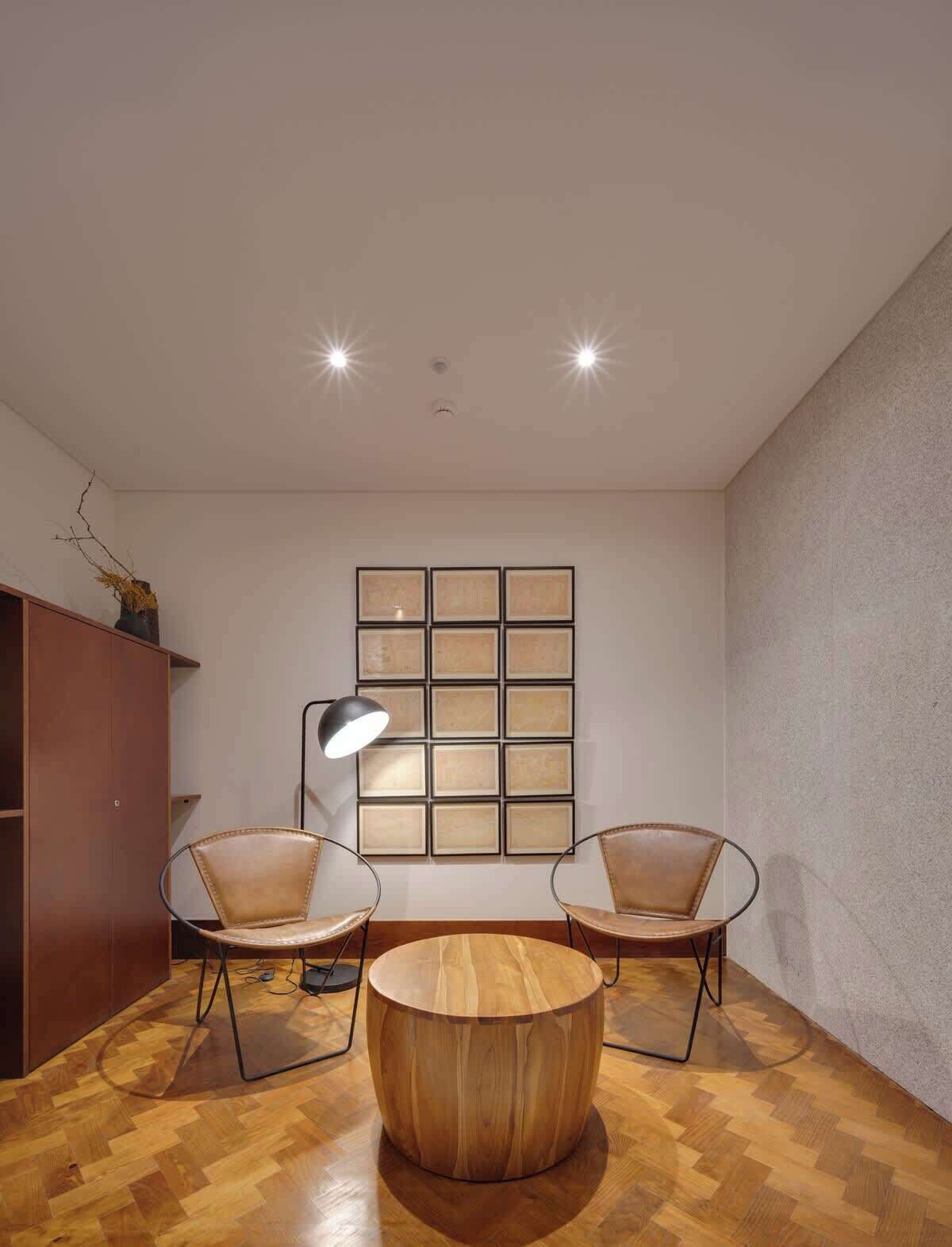 Una habitación moderna con dos sillones de cuero, una mesa de centro de madera, una lámpara de pie y un cuadro colgado en la pared.