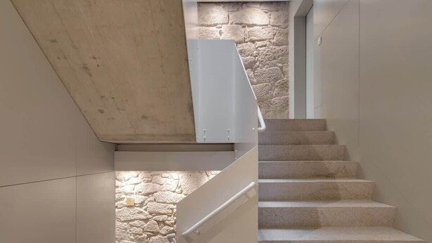 A modern staircase with a stone wall backdrop and minimalist design. - Republica 144 Apartamentos by DA'Home (Porto)