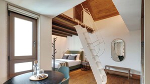 A modern bedroom with a wooden ceiling, a bed with a headboard, a bedside table, and a hanging light fixture. - Republica 144 Apartamentos by DA'Home (Porto)