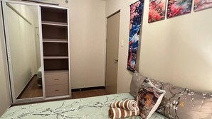 A bedroom with a bed, a wardrobe, and a mirror. - Japan Vibe 2-bedroom condo with Veranda Pool View and AC in vibrant Pasig (Pasig)
