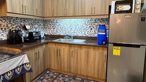 A compact kitchen with wooden cabinets, a stainless steel sink, a microwave, and a refrigerator. - Japan Vibe 2-bedroom condo with Veranda Pool View and AC in vibrant Pasig (Pasig)