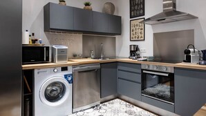 Une cuisine compacte équipée d’un lave-linge, d’un four à micro-ondes, d’un four traditionnel et d’une machine à café.