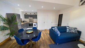 A modern apartment with a dining area, a blue sofa, and a kitchen. - Résidence Thermale - Chez Helder, the Suite 💎 (Vichy)