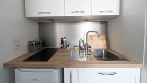 A compact kitchen with white cabinets, a stainless steel sink, and a built-in dishwasher.