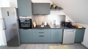 A modern kitchen with grey cabinets, a built-in oven, a dishwasher, and a countertop with various items.