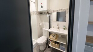 A small, modern bathroom with a toilet, bidet, and a sink with a mirror.