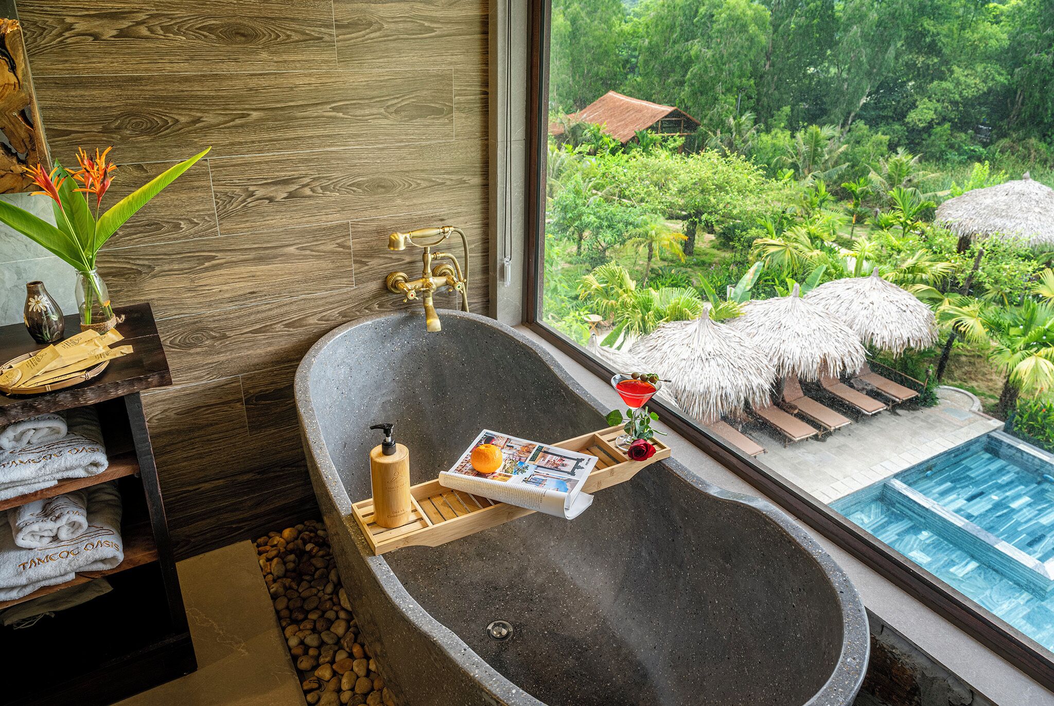 Une baignoire avec un plateau en bois, un magazine et une bouteille.