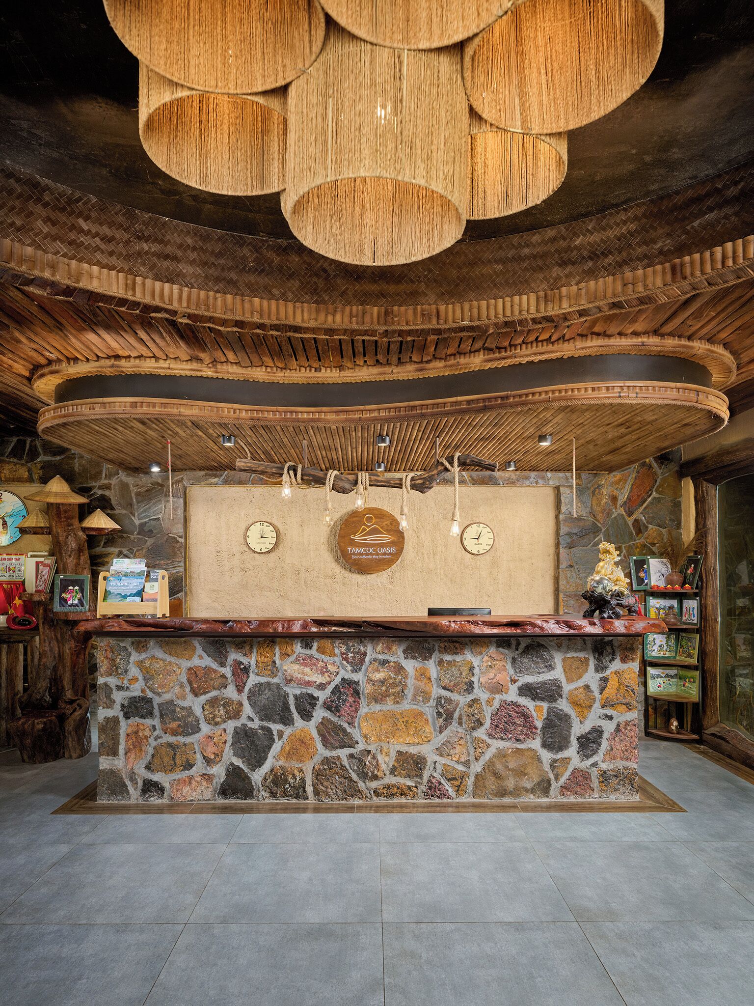 A reception desk with a stone base, wooden ceiling, and a hanging light fixture.