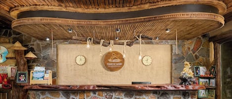 A reception desk with a stone base, wooden ceiling, and a hanging light fixture.