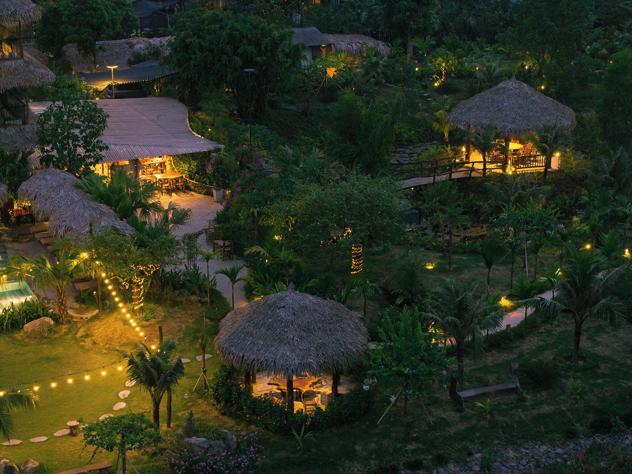 Un resort con cabañas de techo de paja, zonas de estar al aire libre y guirnaldas de luces.