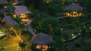 Un resort con cabañas de techo de paja, zonas de estar al aire libre y guirnaldas de luces.