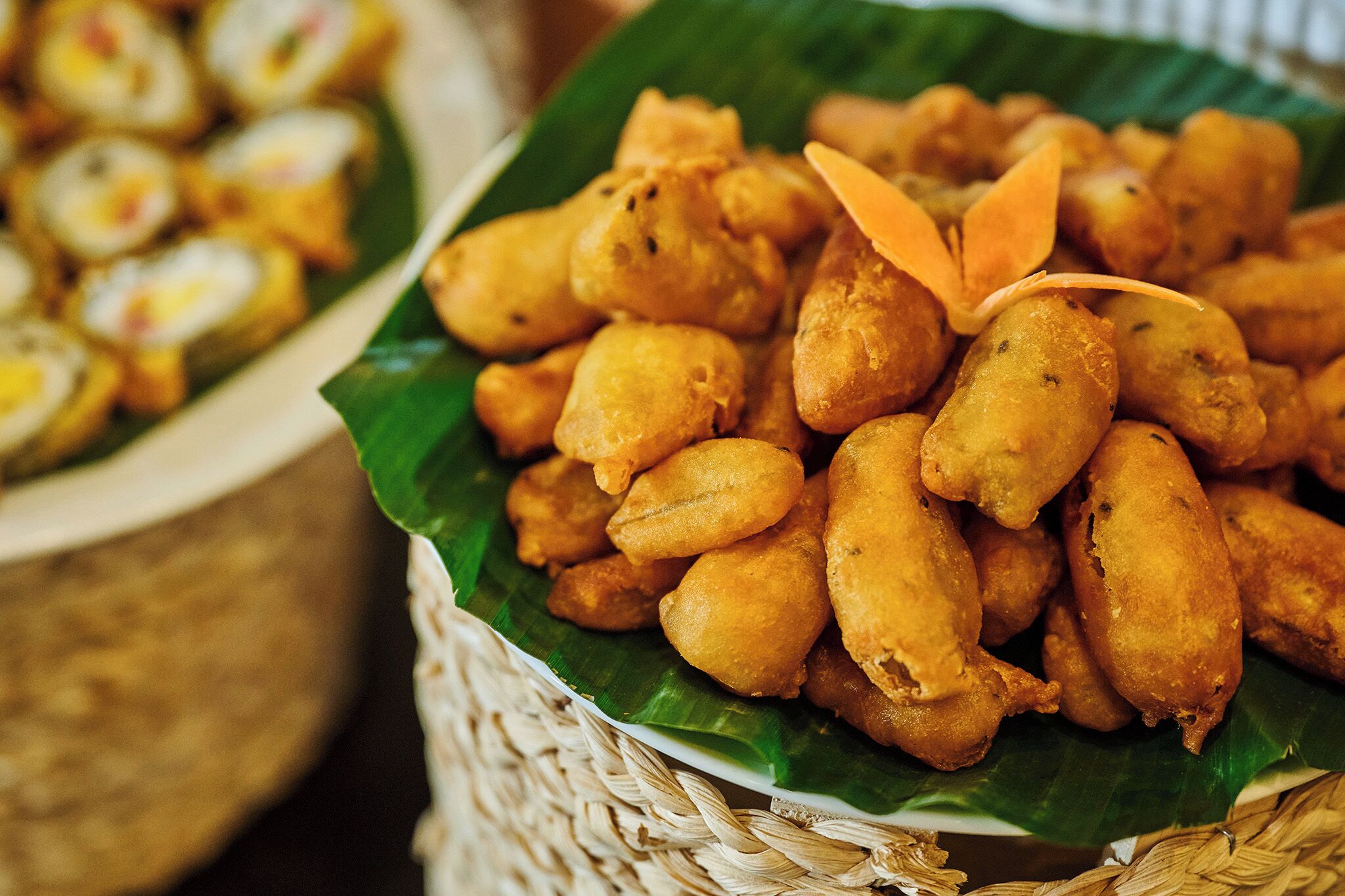 A basket of fried snacks on a banana leaf.