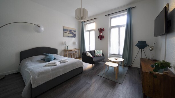 A modern bedroom with a bed, a sofa, a small table, and a TV.