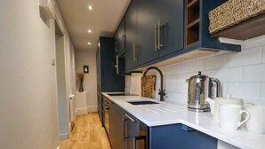 A modern kitchen with dark blue cabinets, a white countertop, and a wooden floor. - Grosvenor Abode, Royal Tunbridge Wells (Royal Tunbridge Wells)