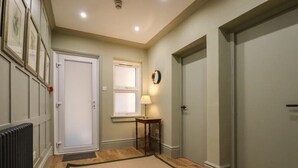 A hallway with a radiator, a door, a window, a lamp, and a rug. - Grosvenor Abode, Royal Tunbridge Wells (Royal Tunbridge Wells)