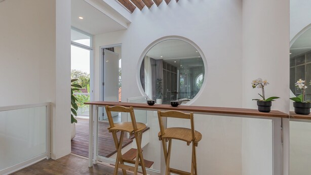 A modern interior with a wooden desk and two chairs, a large round mirror, and potted orchids. - Villa Eudora 2br villa with private pool (Kec. Mengwi - Badung)