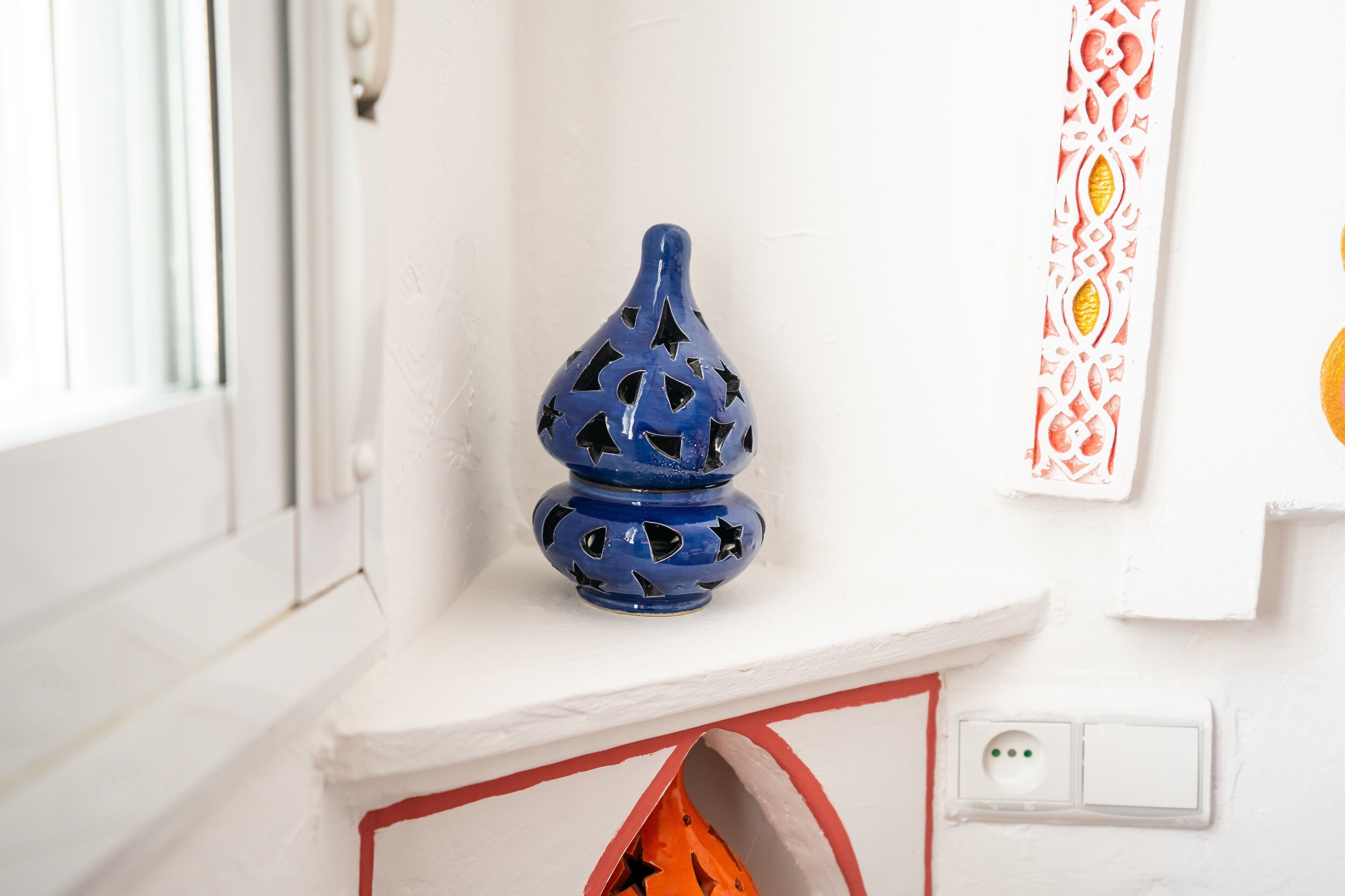 A blue vase with star patterns on a white shelf.