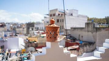 A terracotta lantern atop a white wall, with a cityscape in the background.