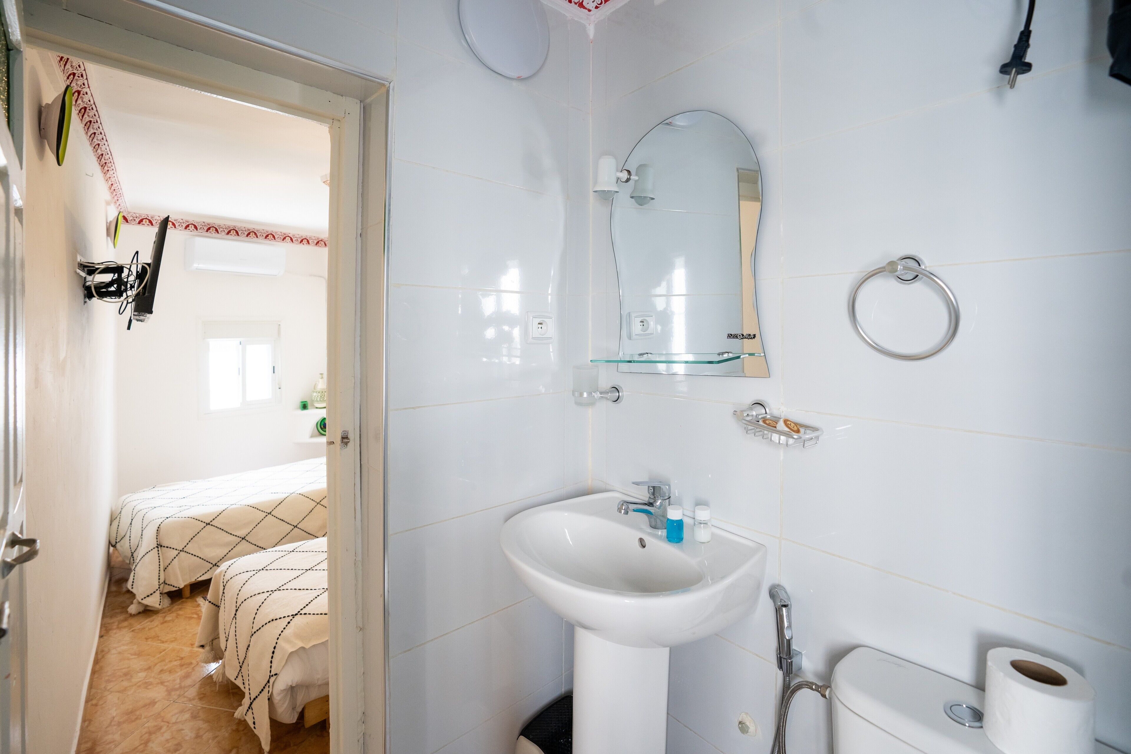 A bathroom with a sink, mirror, toilet, and a shower.