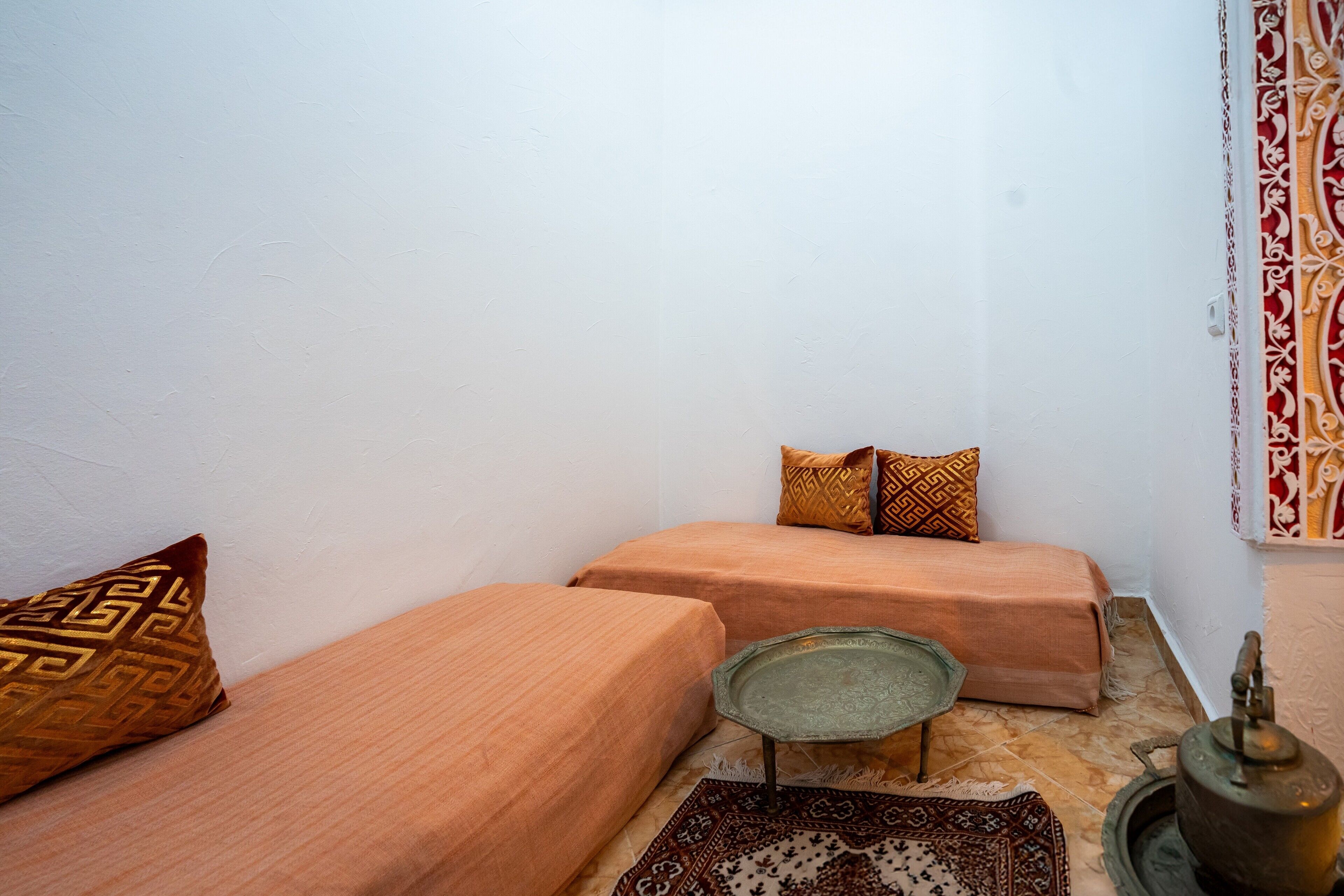 A small, cozy room with two beds, a small table, and a traditional kettle.