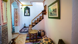 Un pasillo con escalera de madera, alfombras estampadas y decoración tradicional.