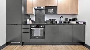 A modern kitchen with a Bosch oven, microwave, and a coffee machine. - Luxury 1 Bedroom Flat with private patio Sleeps 4 (London)
