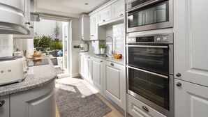 Een moderne keuken met witte kastjes, een inbouwoven en een aanrecht met een broodrooster.