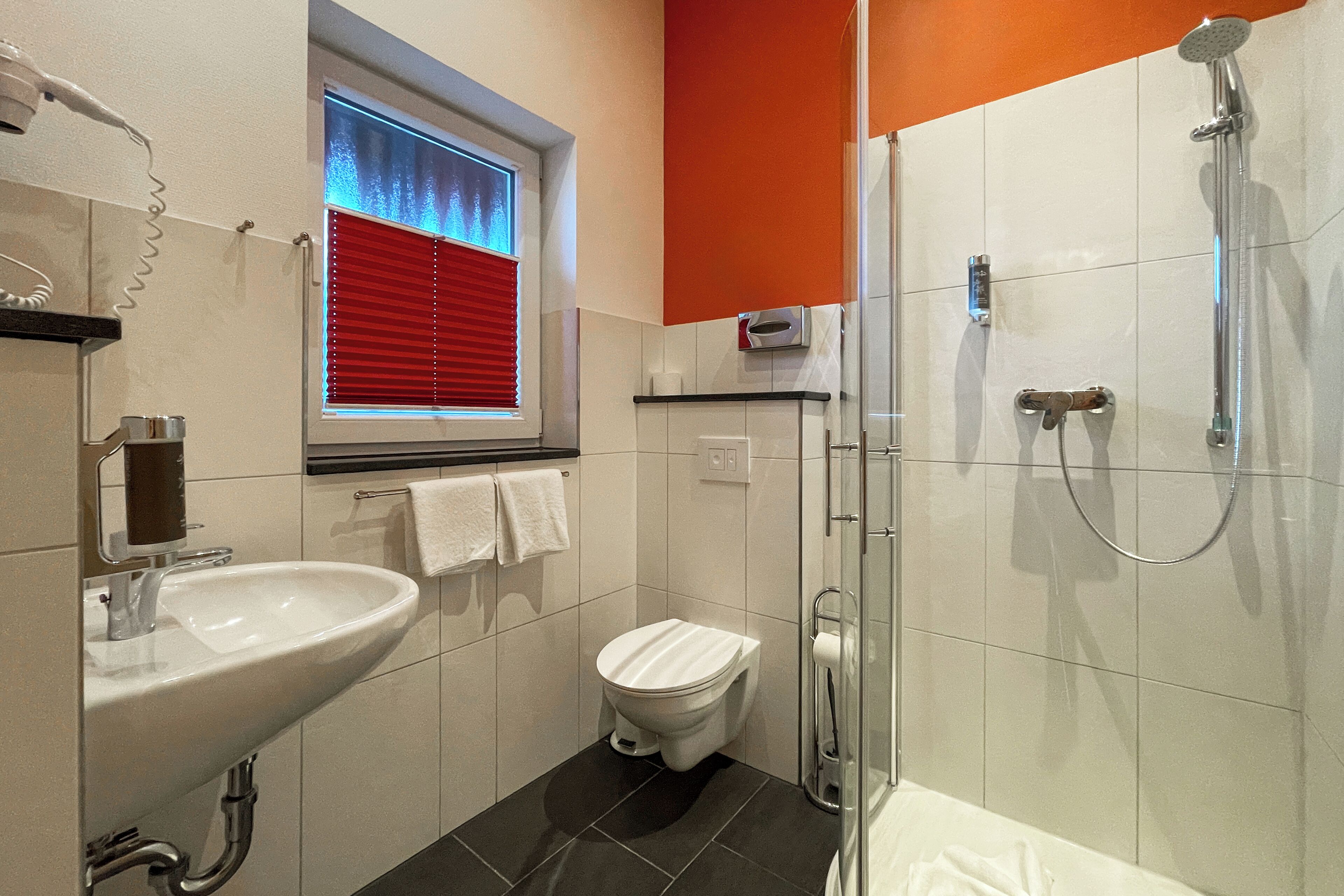 A bathroom with a sink, toilet, and shower.