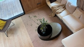 Una sala de estar moderna con un ventanal grande, un sofá, una mesa de centro y un televisor montado en la pared.