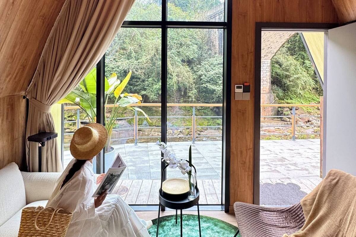 A cozy room with a large window, a green rug, a wicker basket, and a chair.