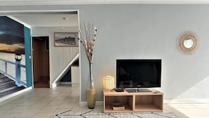 Ein Wohnzimmer mit Fernseher, einer Vase und einer Lampe.