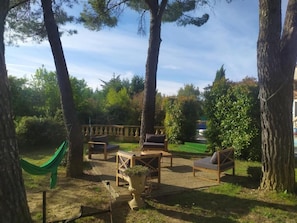 Un espacio al aire libre con mobiliario de madera, una hamaca y una planta en maceta.