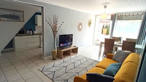 Ein Wohnzimmer mit einer Couch, einem Fernseher, einer Kaffeemaschine und einer dekorativen Vase.