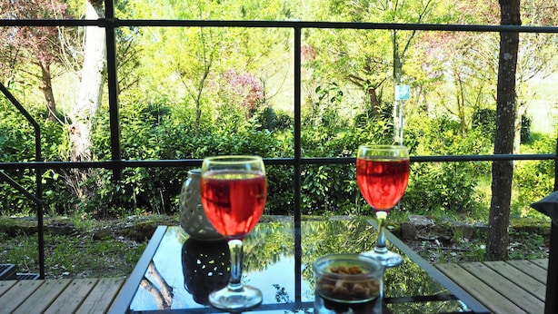 Uma mesa de vidro com duas taças de vinho e um castiçal.