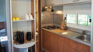 Uma cozinha compacta com fogão a gás, pia e janela com vista para o verde.