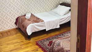 A small room with a bed, a hanging light fixture, and a fan.