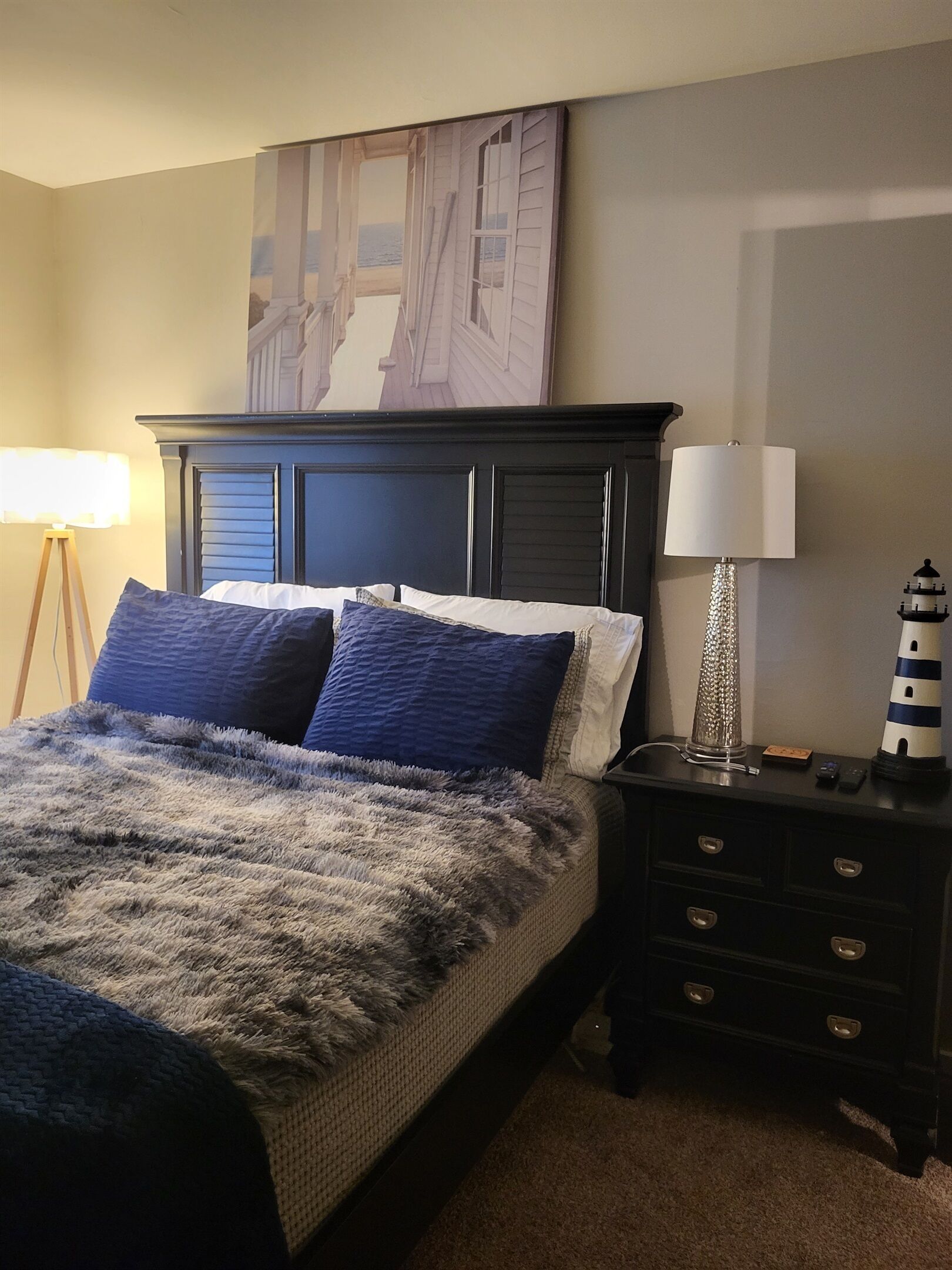 Een slaapkamer met een groot bed, twee nachtkastjes, een lamp en een schilderij aan de muur.
