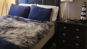 A bedroom with a large bed, two nightstands, a lamp, and a painting on the wall. - Galaxy on Medical Mile Come Thrive! (Grand Rapids)