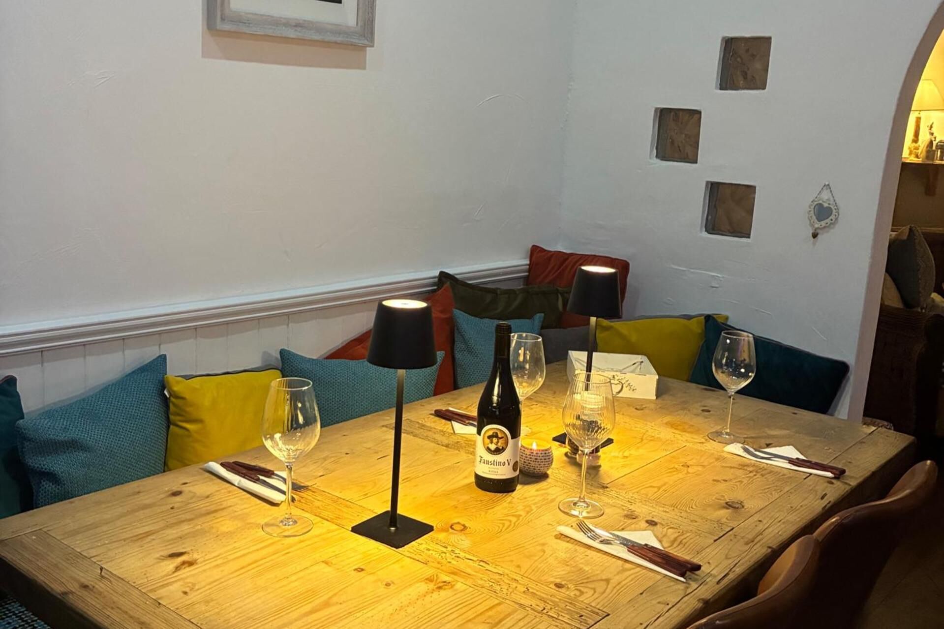 A wooden dining table with wine glasses, a bottle, and a candle.