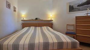 A bedroom with a bed, bedside lamps, a dresser, and a framed picture on the wall. - Modern vacation apartment "Wellenkieker" with balcony and parking space in Graal-Müritz (Graal-Müritz)