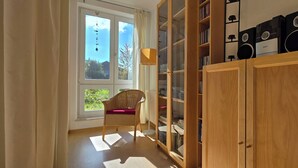 A room with a large window, a wicker chair, a wooden cabinet with glass doors, and a bookshelf. - Modern vacation apartment "Wellenkieker" with balcony and parking space in Graal-Müritz (Graal-Müritz)