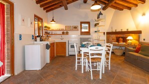A kitchen with a dining table, chairs, a refrigerator, and a stove. - Holiday Home 'I Mandrioli' with Private Terrace, Wi-Fi and Air Conditioning (Casale Marittimo)