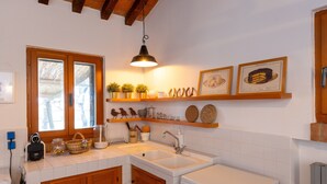 A kitchen with wooden cabinets, a double sink, a stove, and shelves with decorative items. - Holiday Home 'I Mandrioli' with Private Terrace, Wi-Fi and Air Conditioning (Casale Marittimo)
